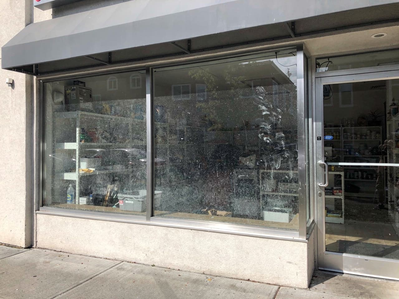 A storefront window dulled by fingerprints, grime, and street film before cleaning